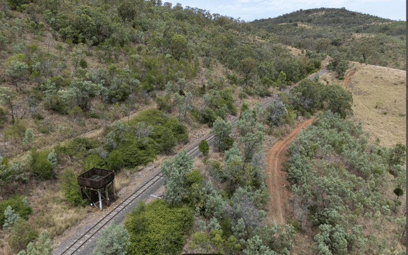 Aerial view of a railway track with surrounding trees and hills.